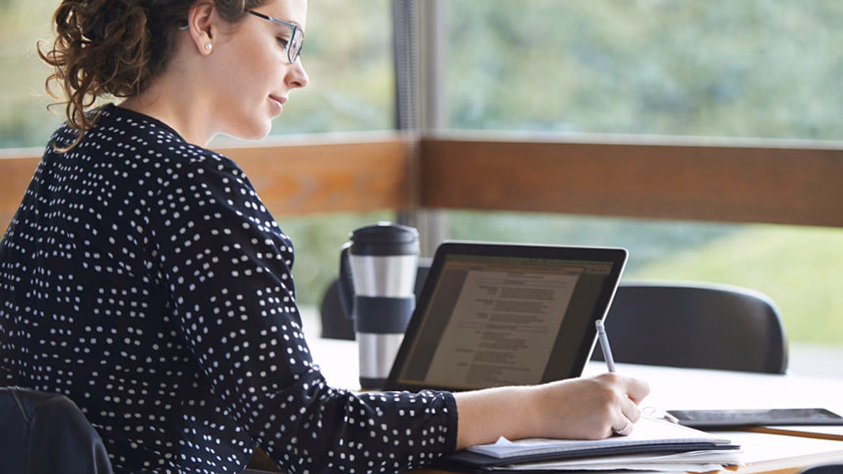 A technical writer writing specifications on their computer while researching