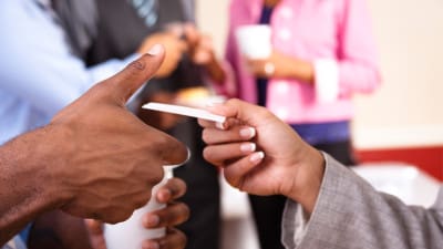 person handing business card to another professional