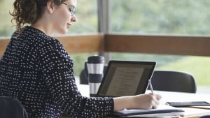 A technical writer writing specifications on their computer while researching