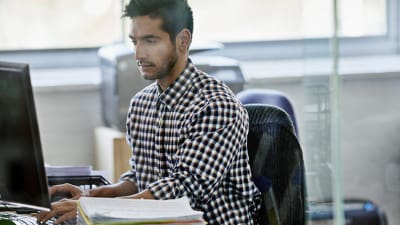 Male editorial assistant working at computer